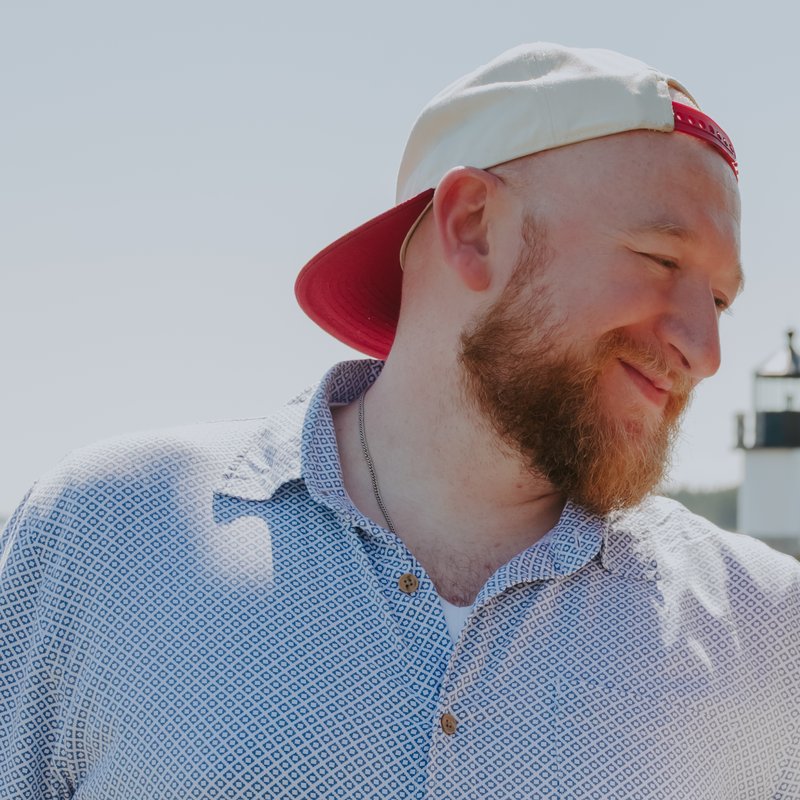 Logan Thome smiling outdoors in a backwards cap