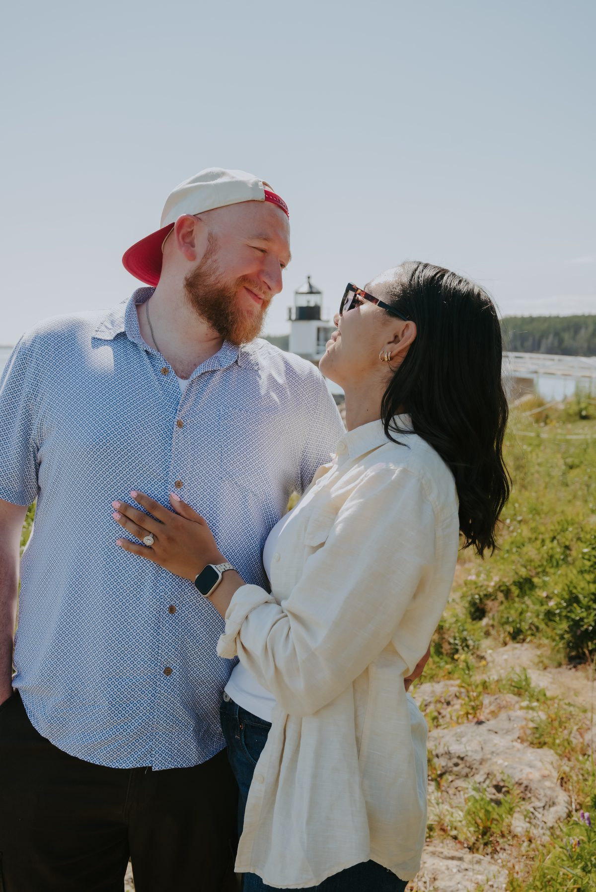 Logan and Kiani smiling at each other in front of a lighthouse